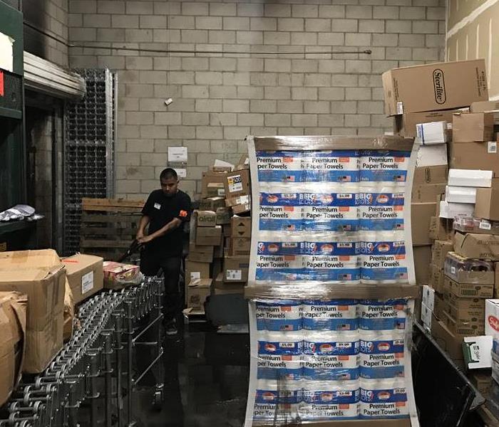 Team member extracting water in warehouse full of boxes.