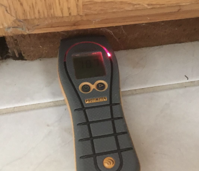 a moisture meter set up on the baseboards of a home
