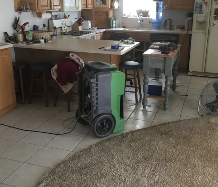 the living room and kitchen area of a home with a dehumidifier set up