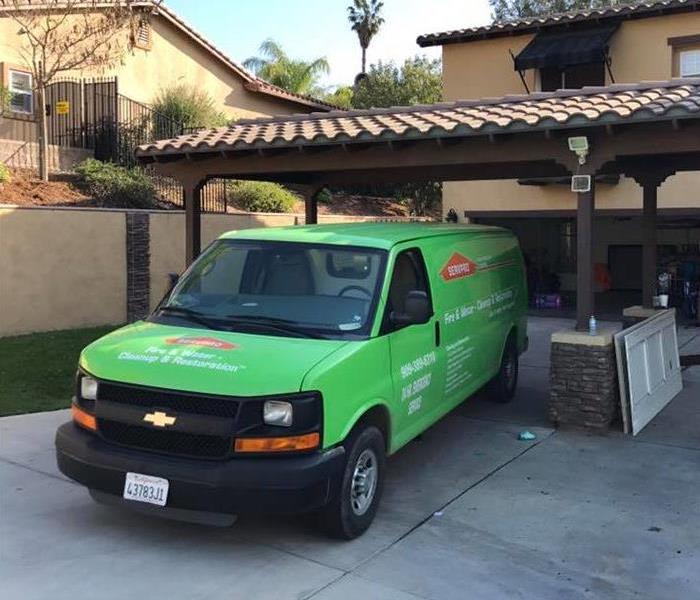 Green SERVPRO truck parked outside home.